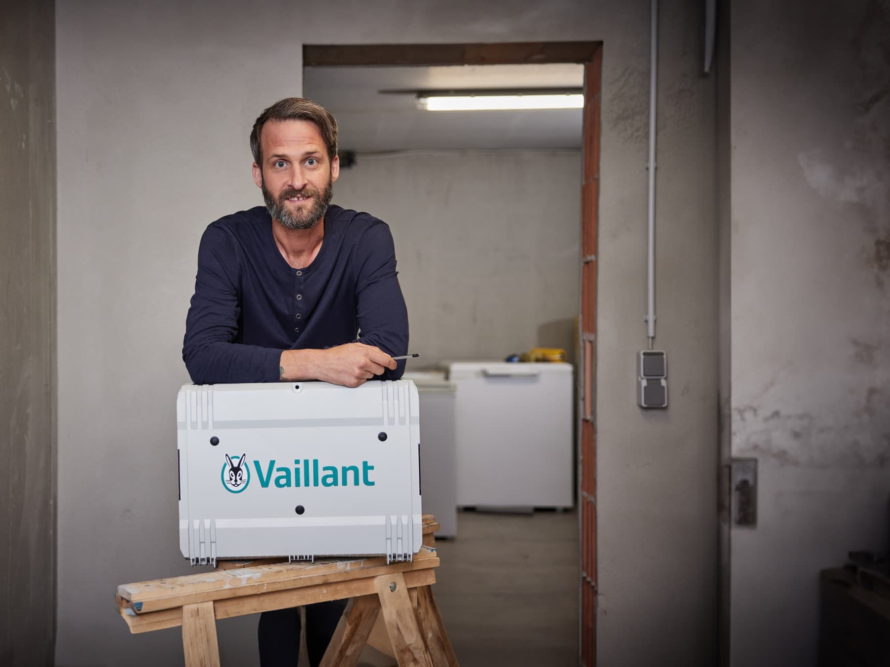 Un installateur appuyé sur sa boîte à outils Vaillant