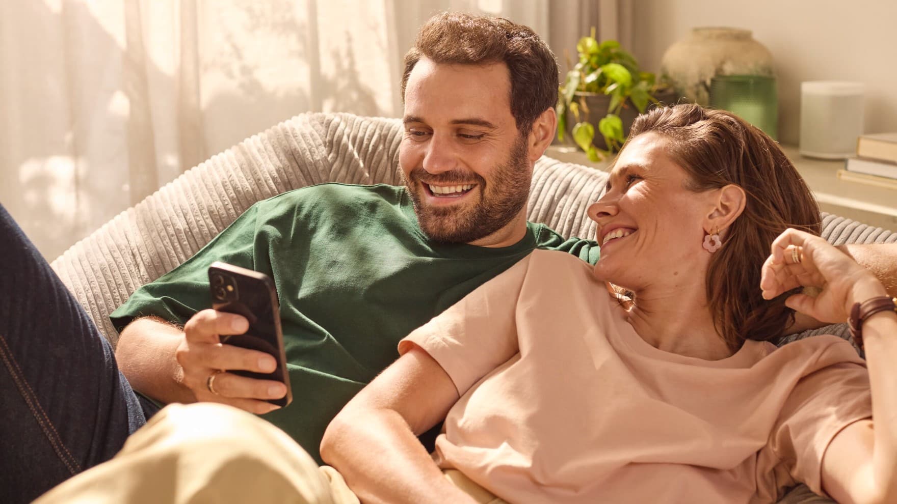 Couple sitting on couch looking at a phone