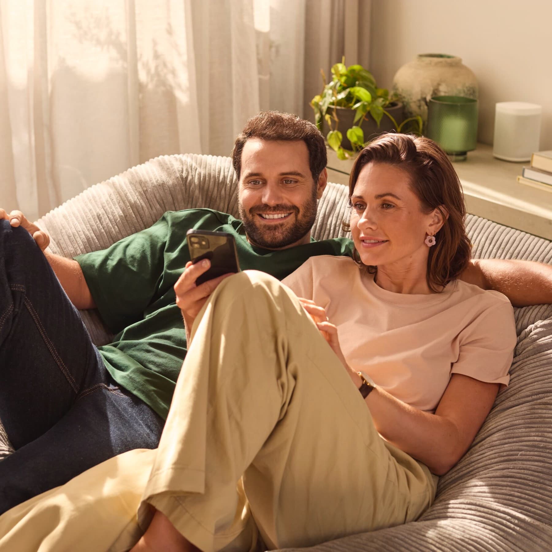 Couple assis sur un canapé regardant un smartphone