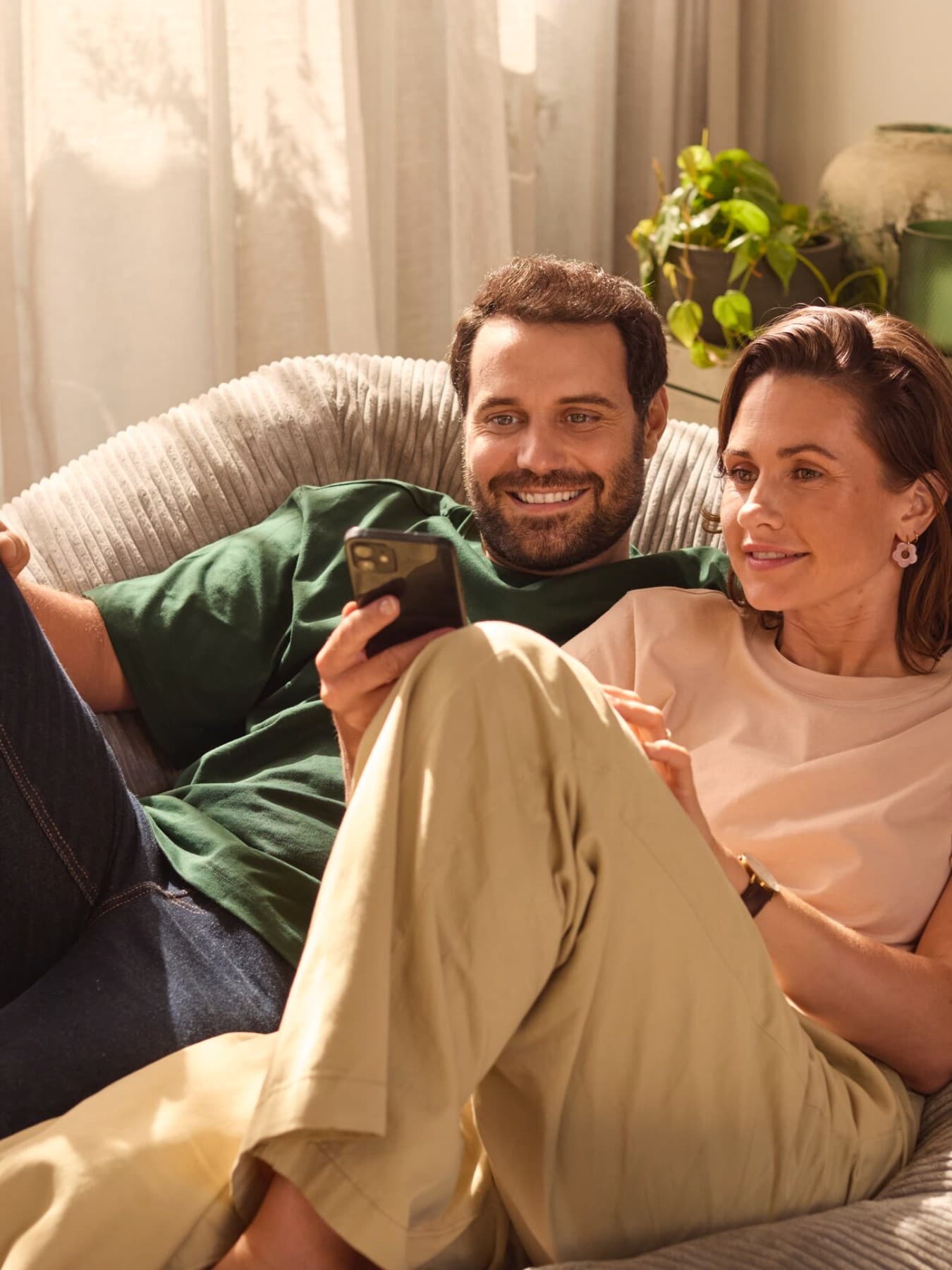 Couple assis sur un canapé regardant un smartphone