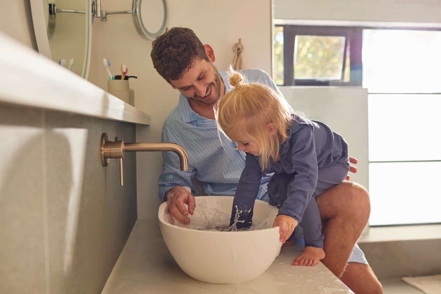 A father and a daughter playing with water in a sink