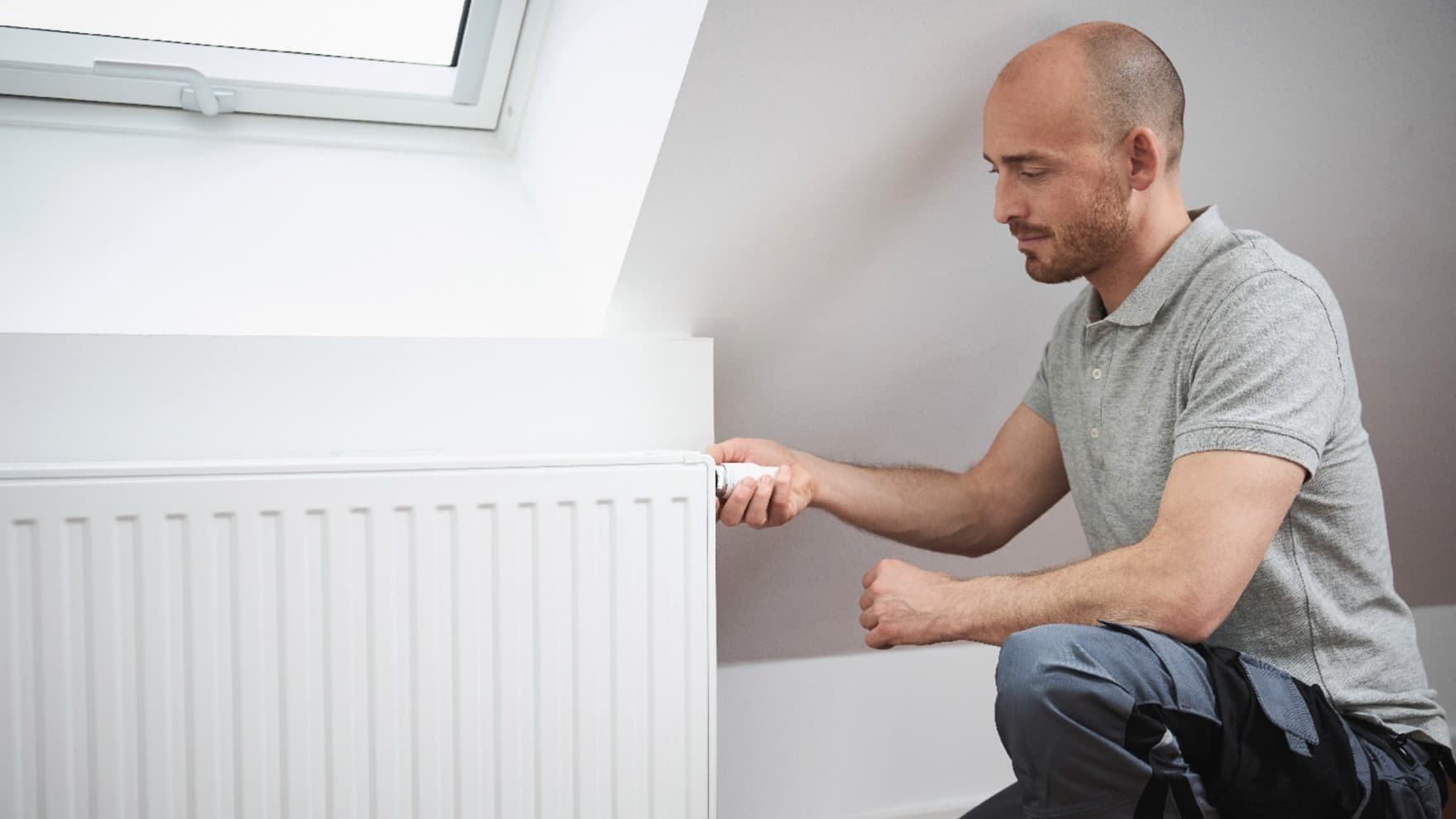 Man turning the thermostat on a radiator