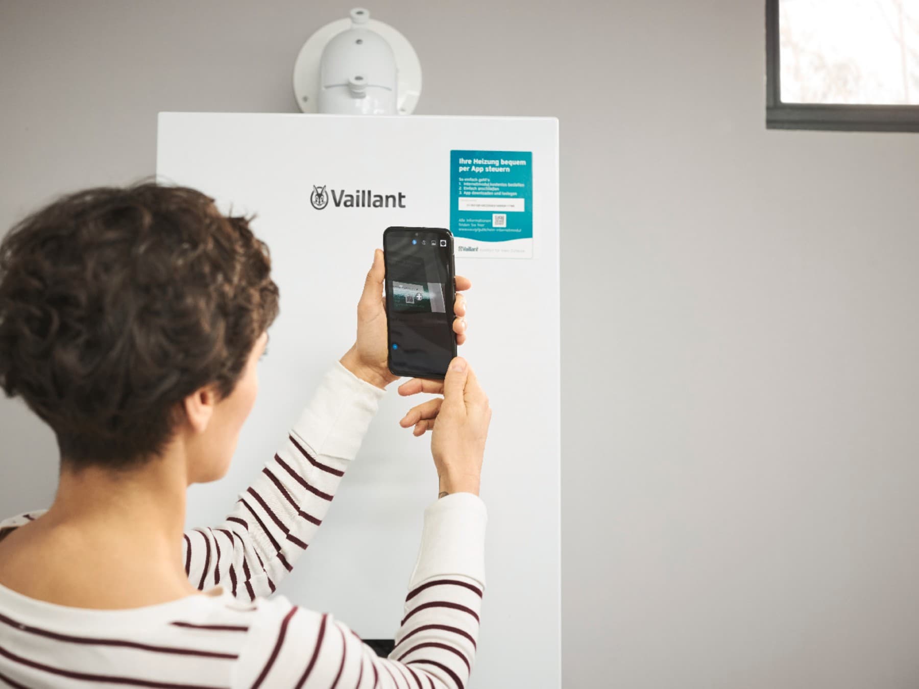 woman is scanning QR-Code on heating device with her smartphone