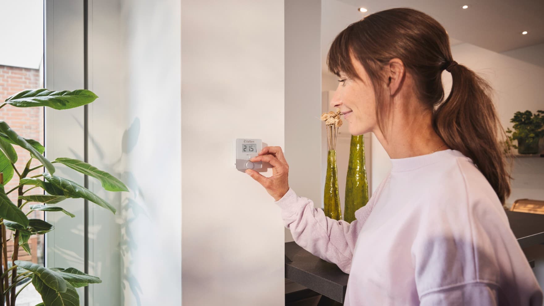 Femme utilisant le thermostat sensoROOM de Vaillant
