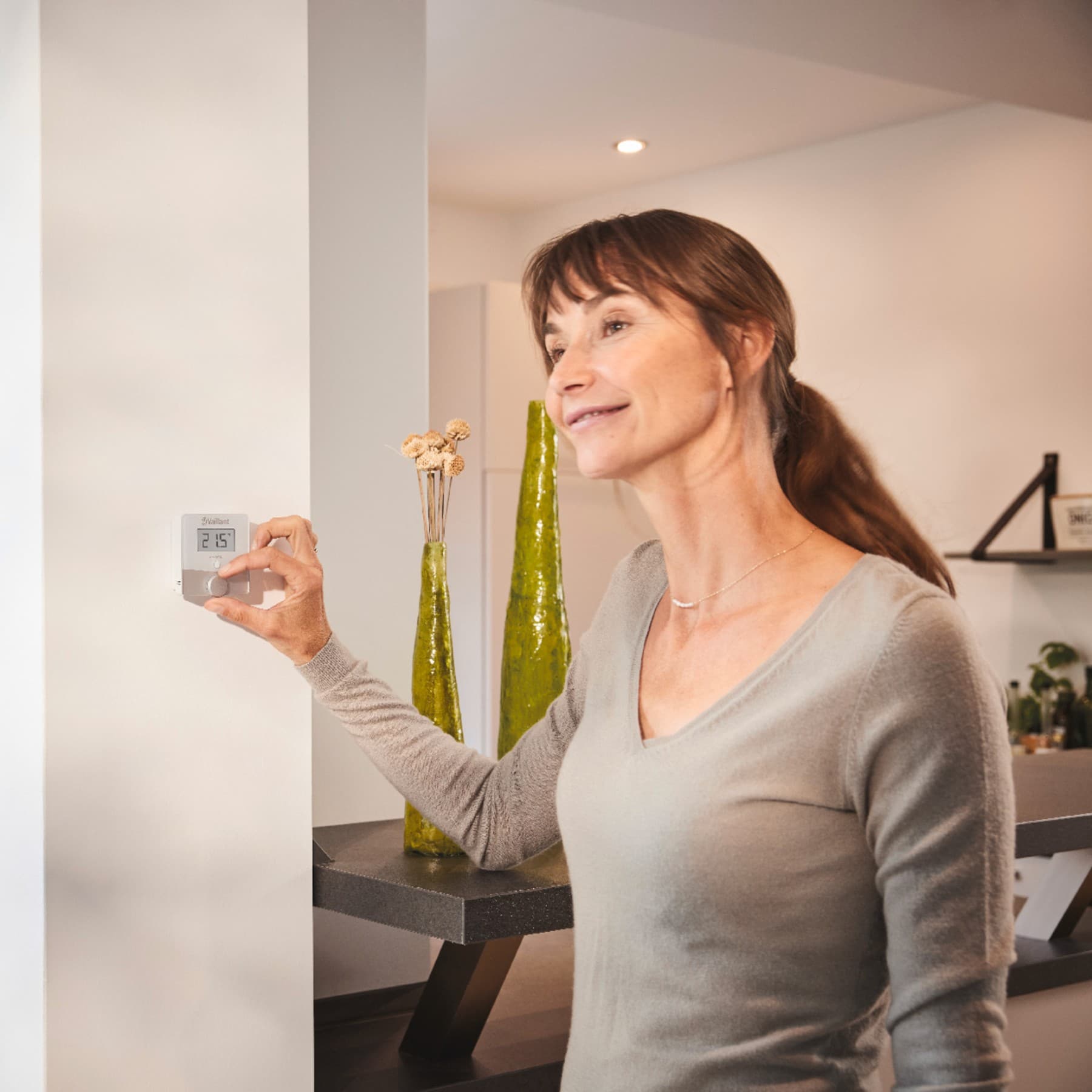Woman turning a thermostat on the wall