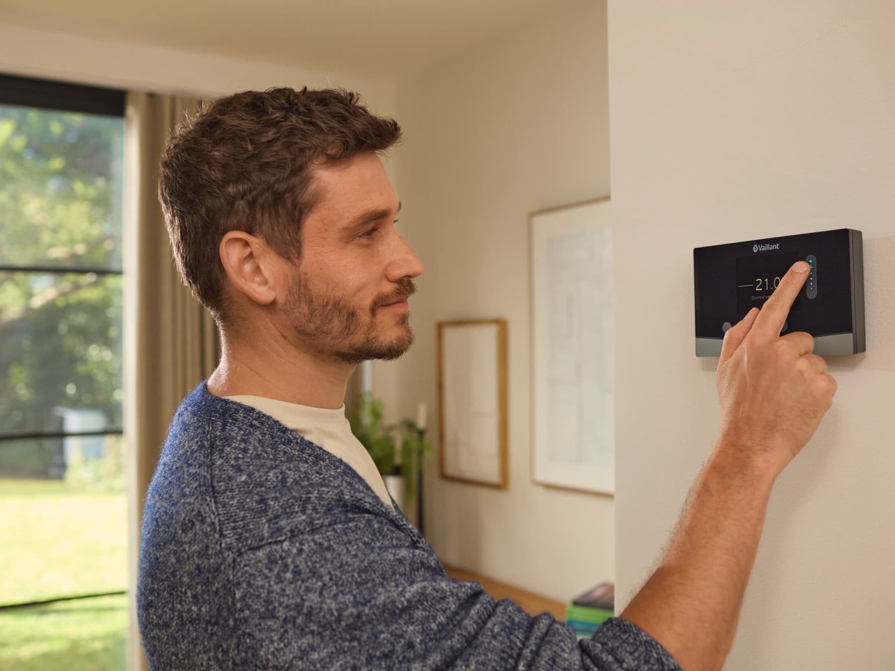 A man is adjusting the settings on his Vaillant room thermostat