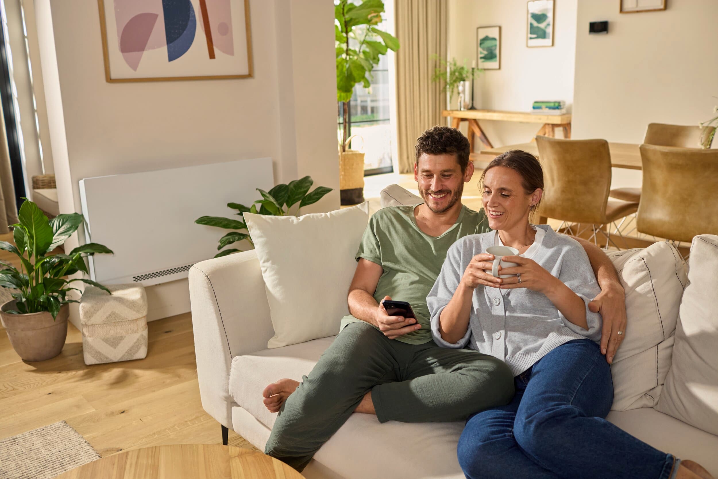 Couple relaxing on the couch with an aroVAIR plus fan coil unit in the background