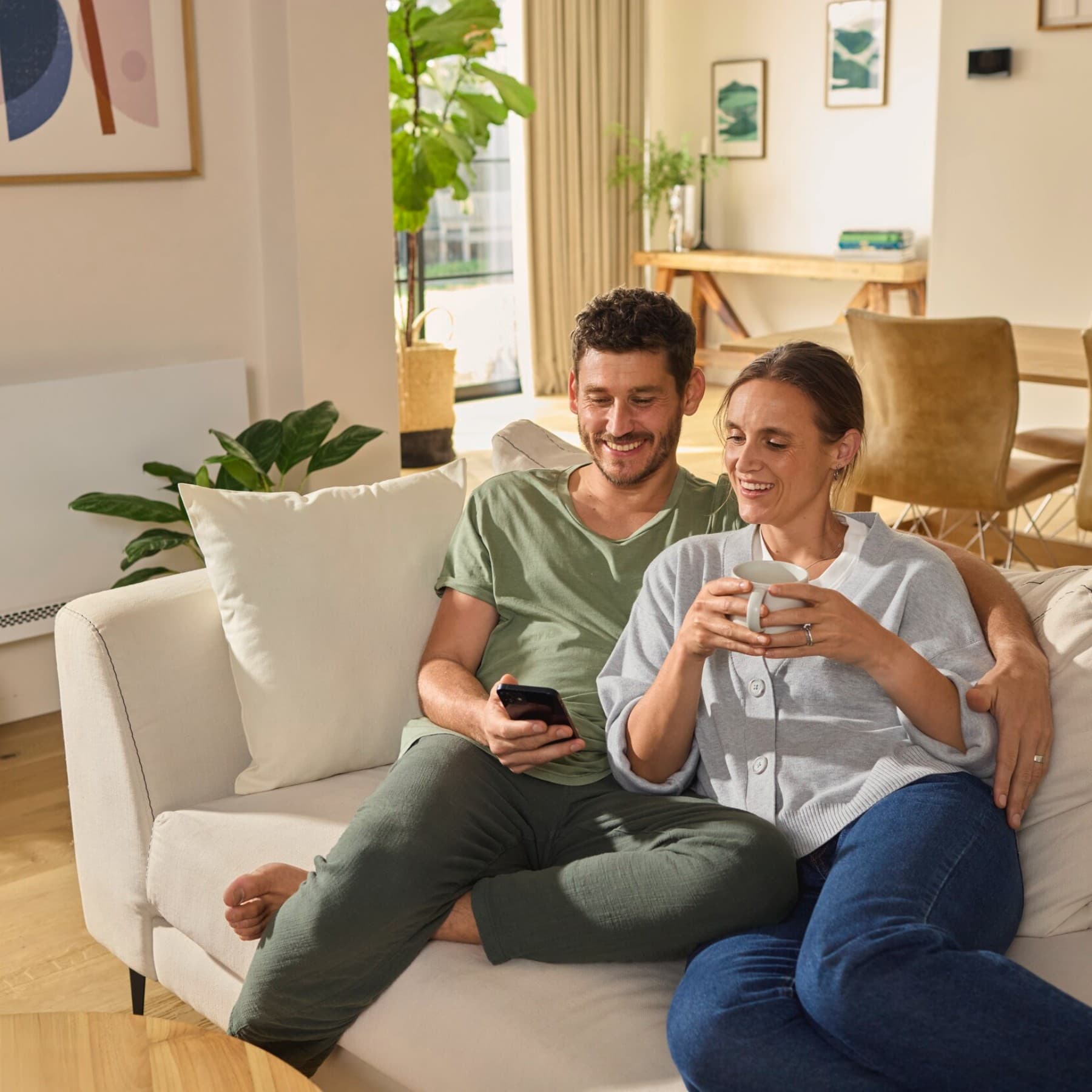 Un couple assis sur le canapé, les yeux rivés sur un smartphone