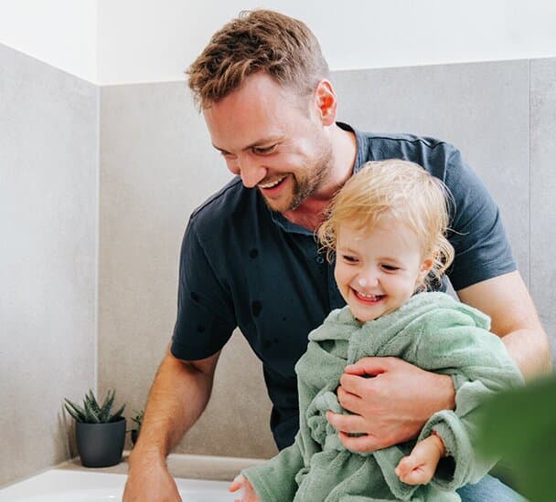 Father and child sitting by the bathtub.