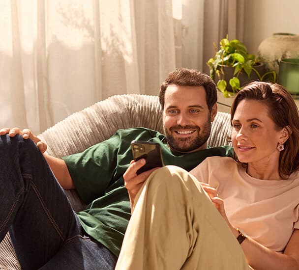 Couple sitting on the couch looking at a smartphone