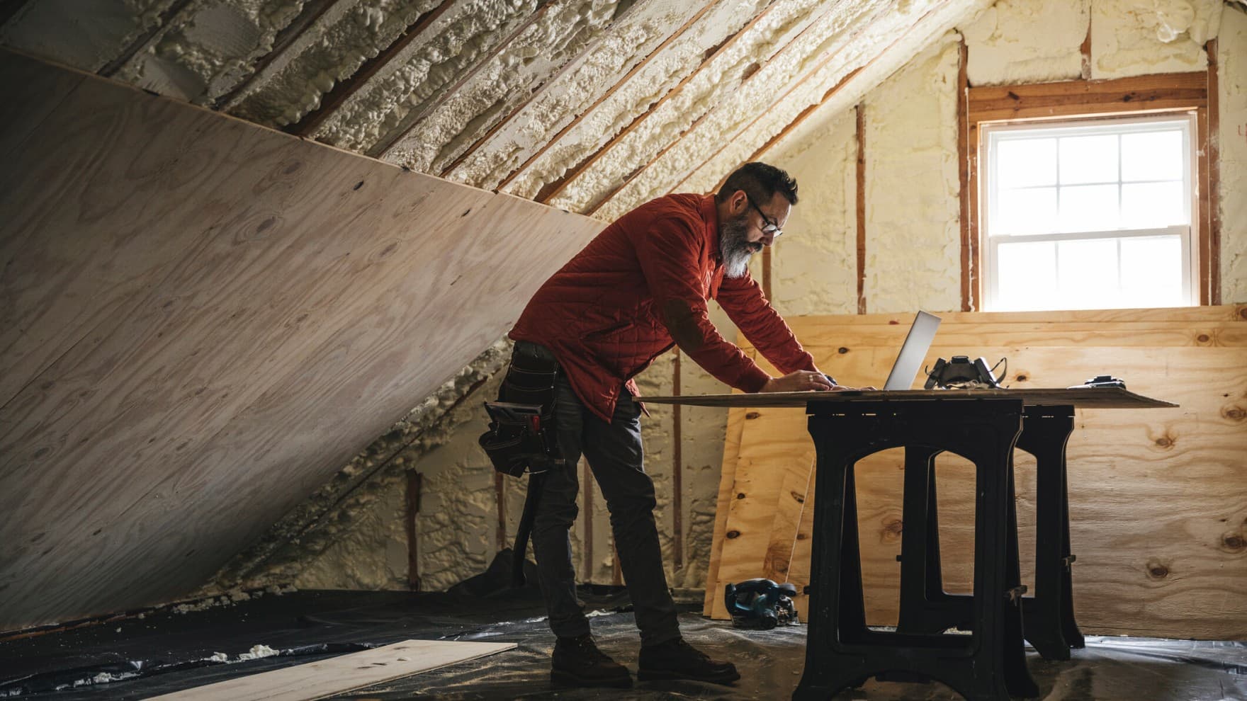 Carpenter looking at laptop during home insulation