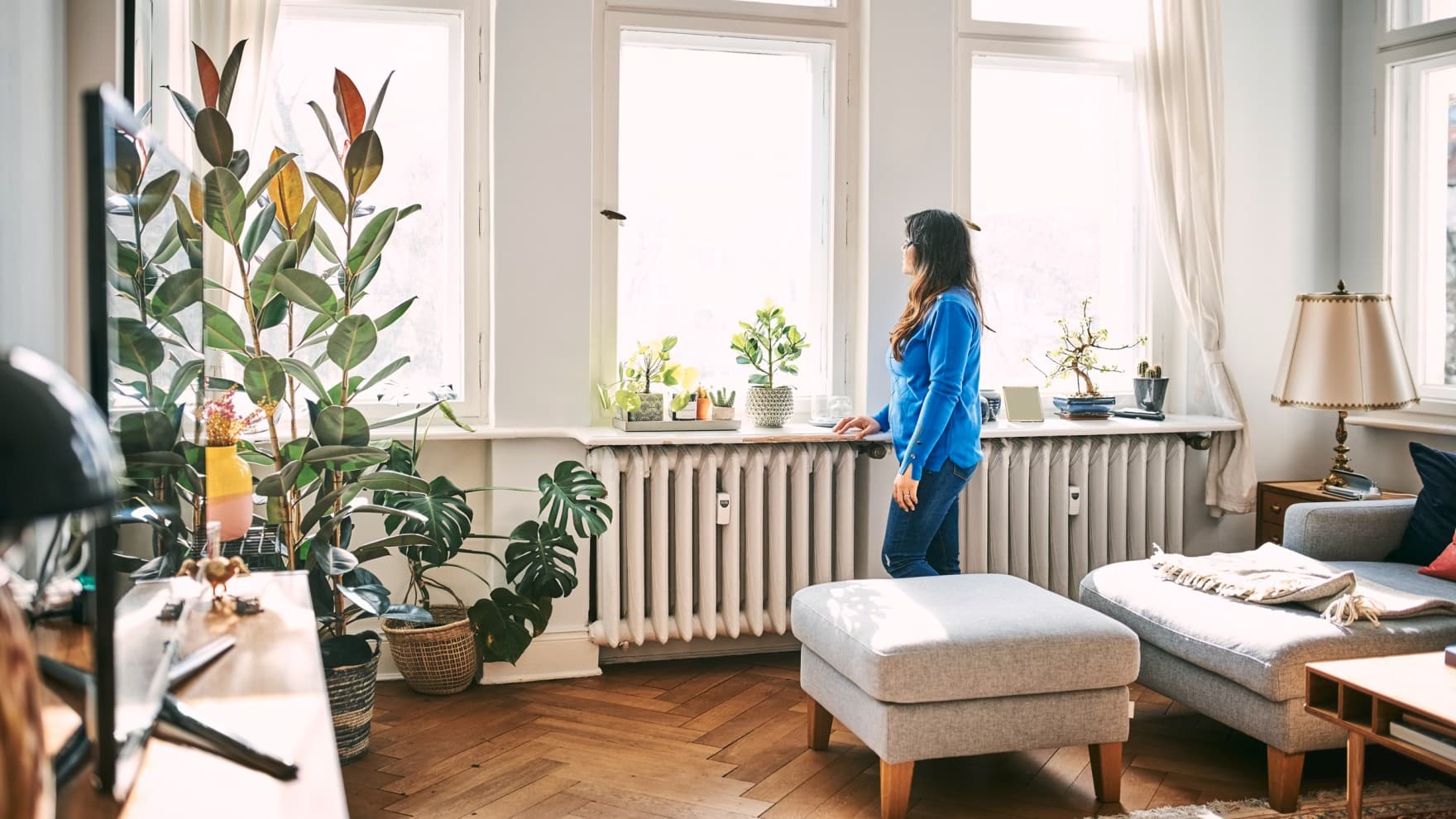 Woman standing in the living room in front of the windows looking out