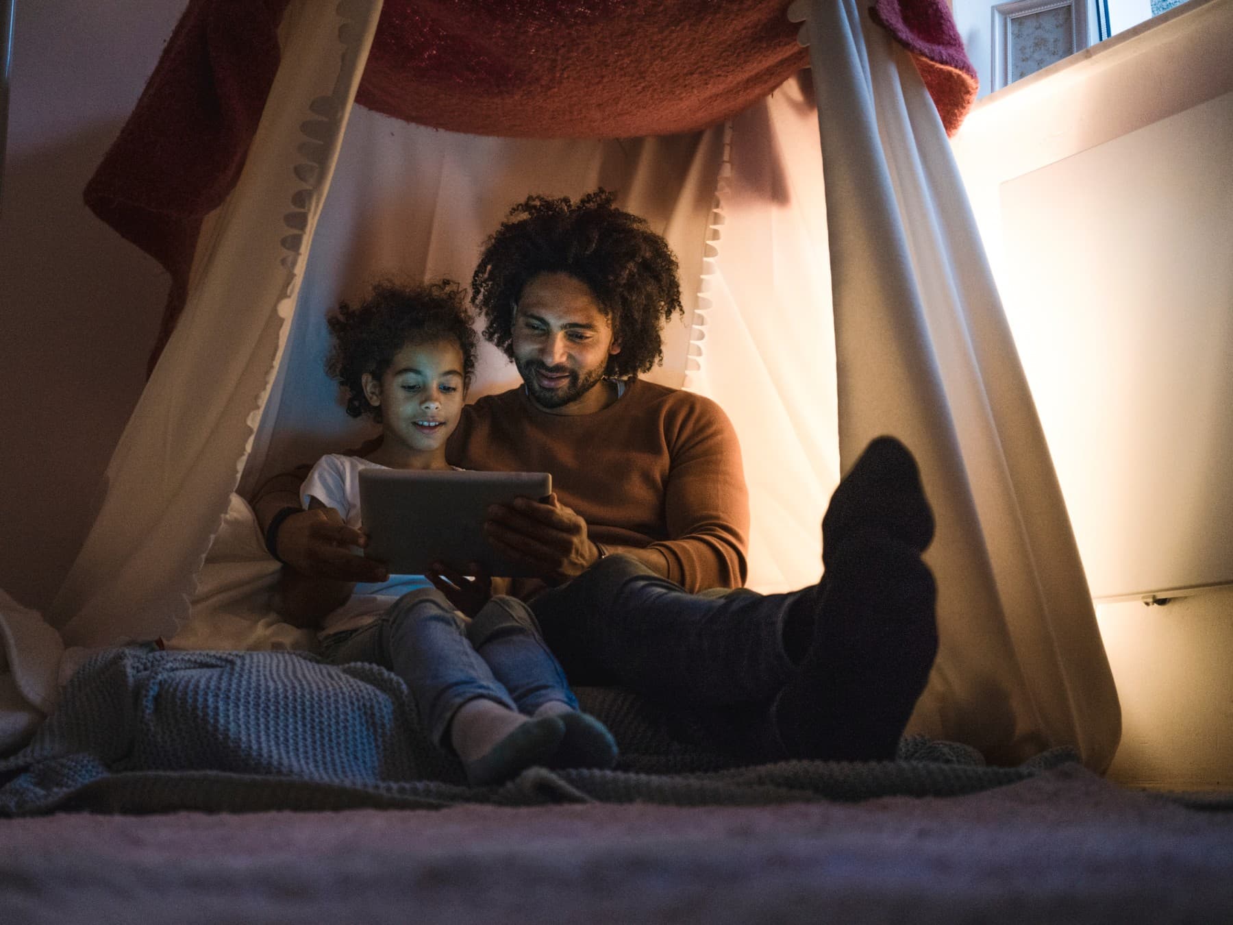 Father and daughter are sitting on the floor and reading