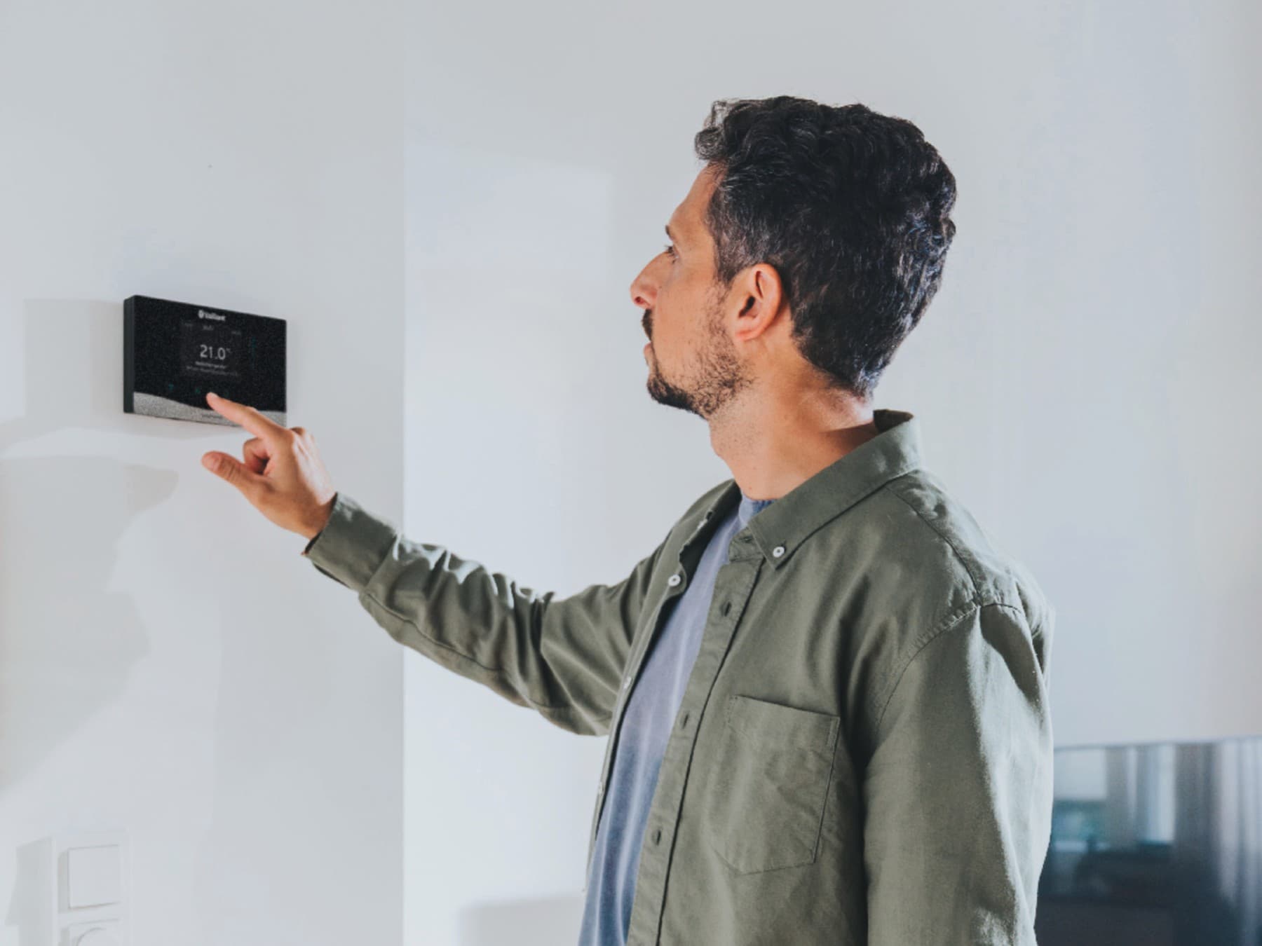 L'homme utilise le régulateur de chauffage sensoCOMFORT.