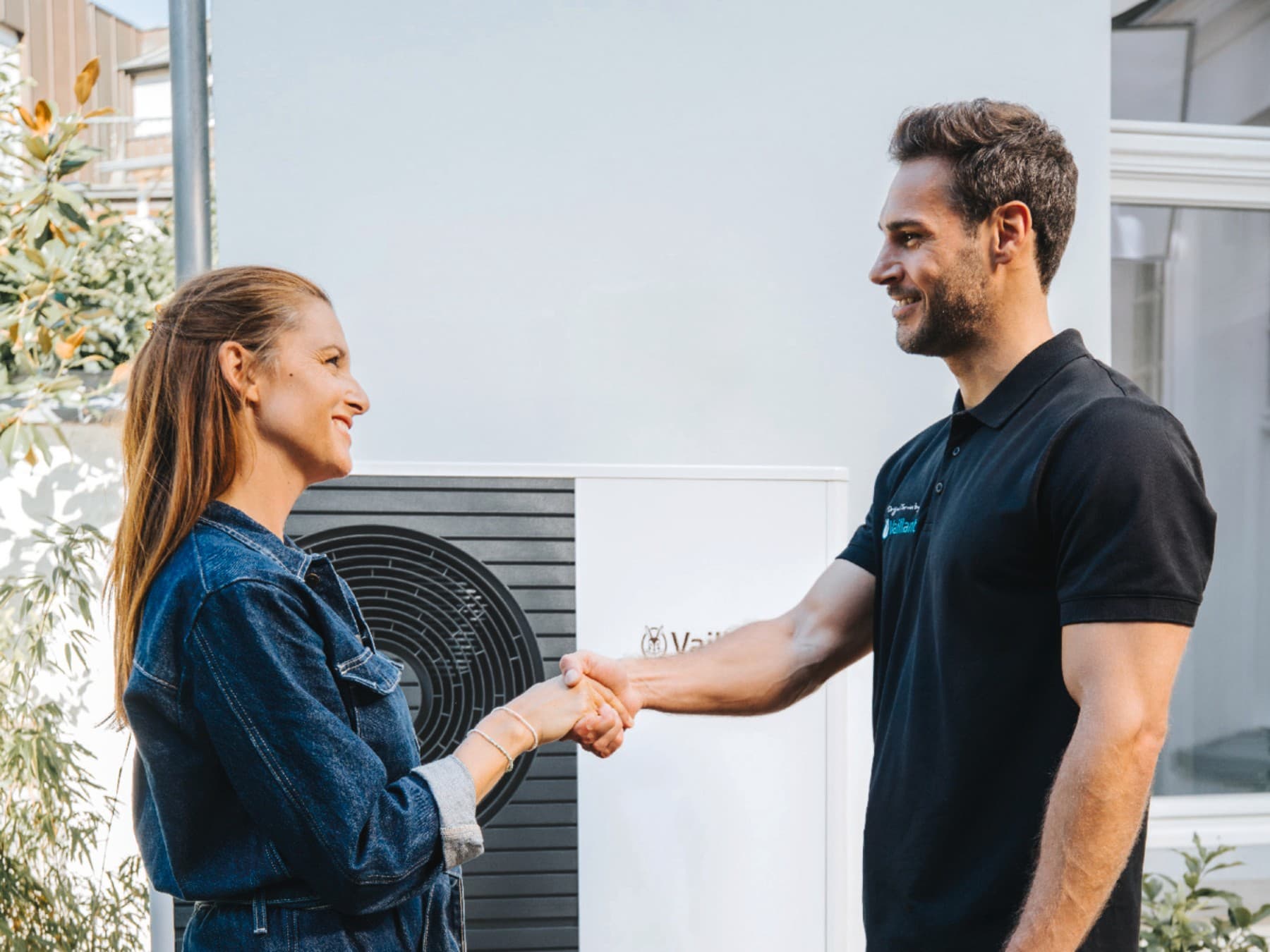 Installer and homeowner in front of a heat pump