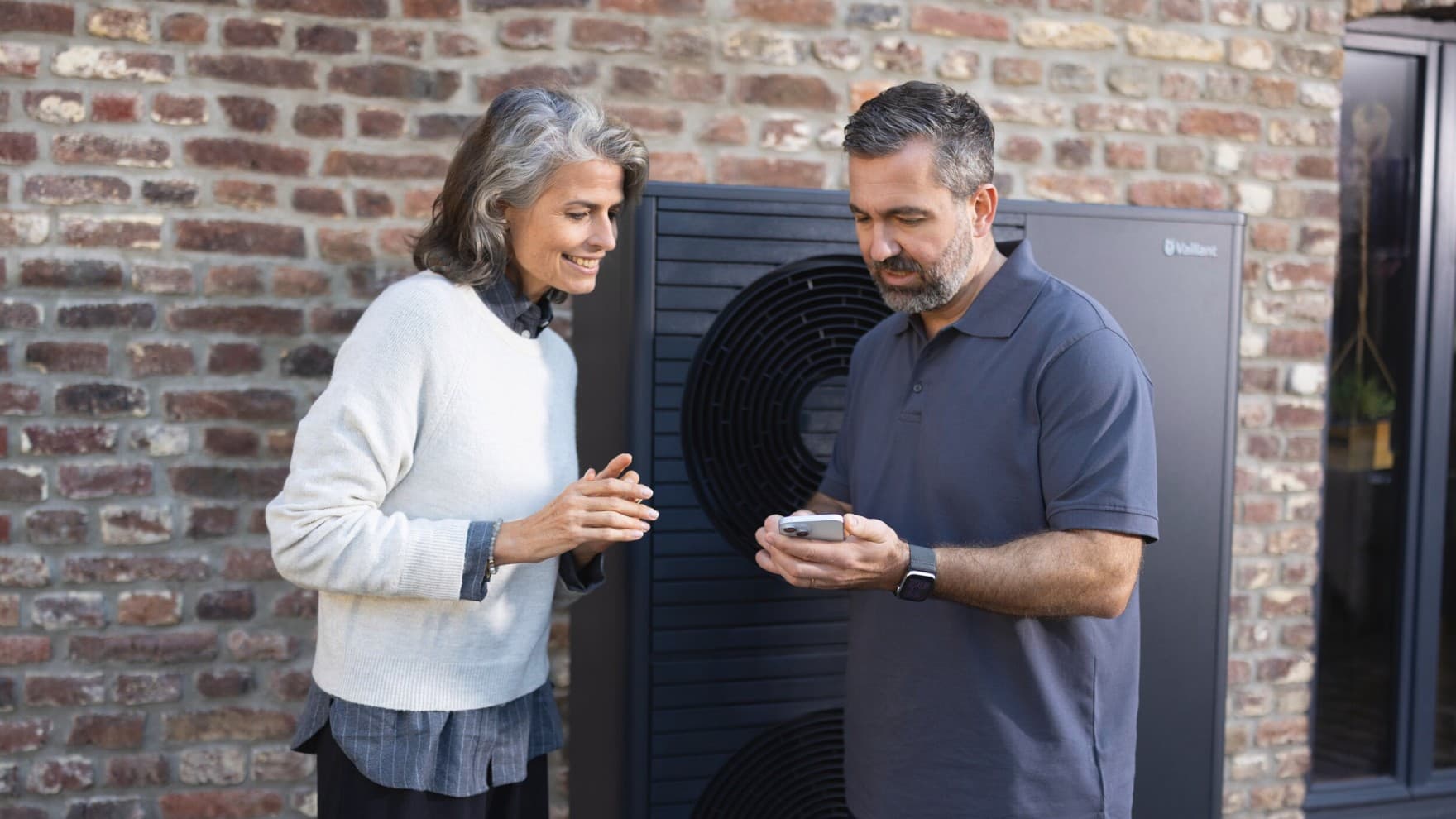 L'installateur explique l'application myVaillant à une femme.