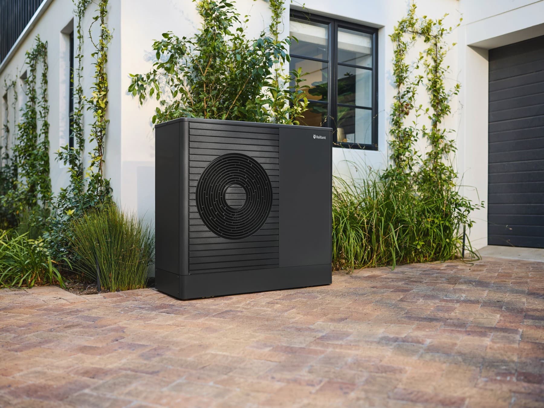 Anthrazite heat pump in front of house