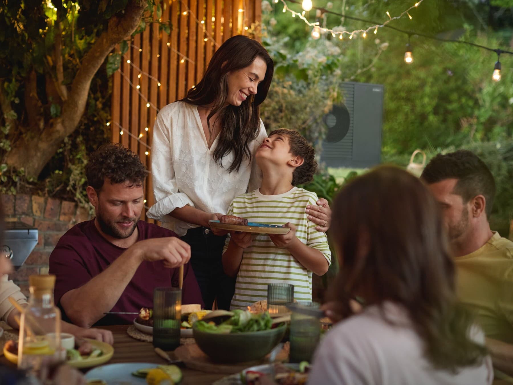 Family enjoying a barbecue in the garden with friends