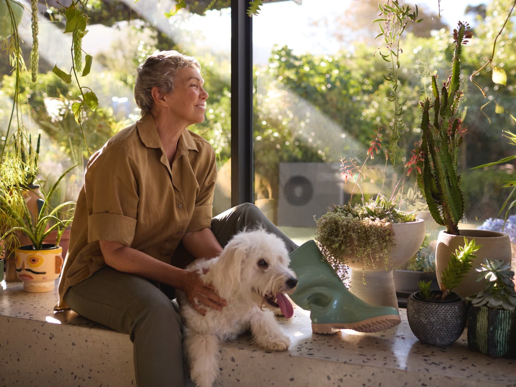 Woman sitting with her dog at the window with heat pump in the garden