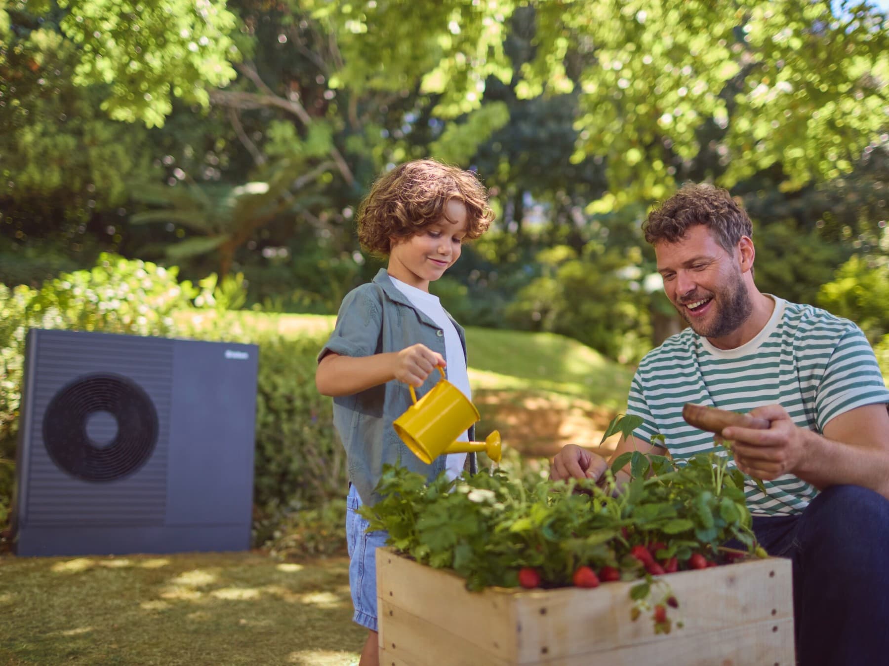 Homme jardinant avec son fils. Unité extérieure d'une pompe à chaleur dans le jardin.
