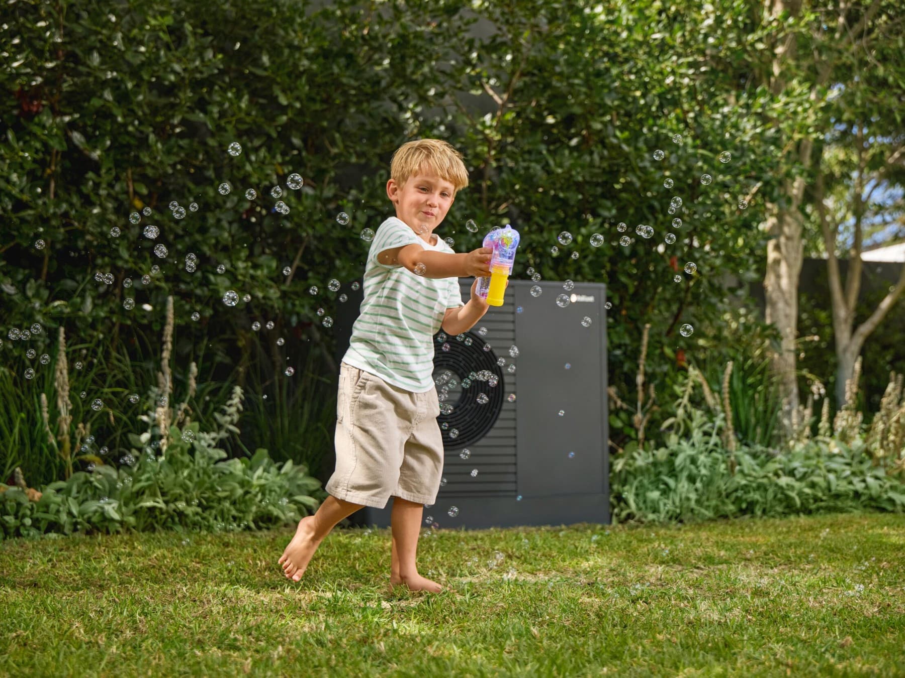 Boy blowing bubbles in front of a heat pump