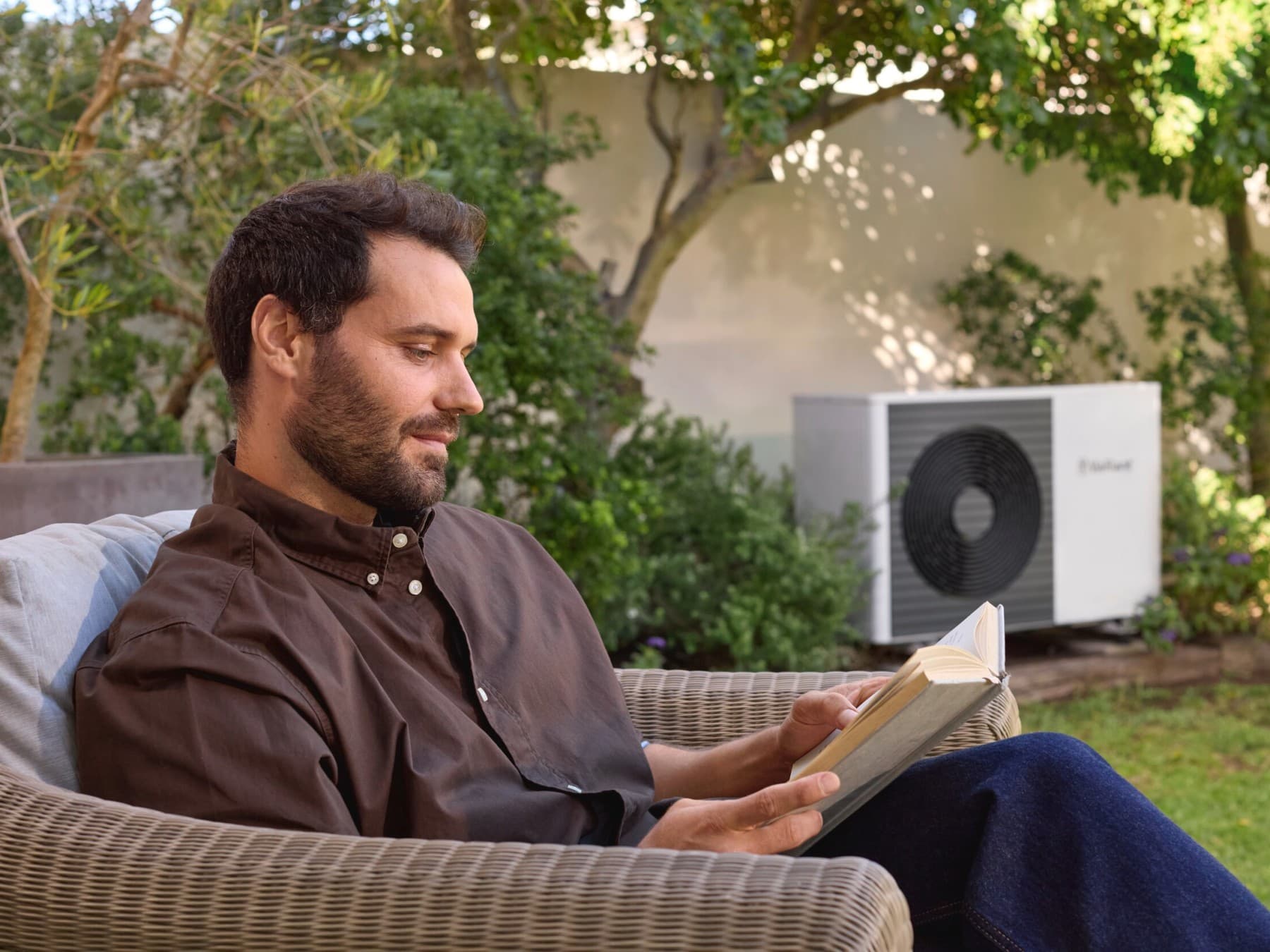 heat pump outdoor unit in a garden with the owner sitting next to it