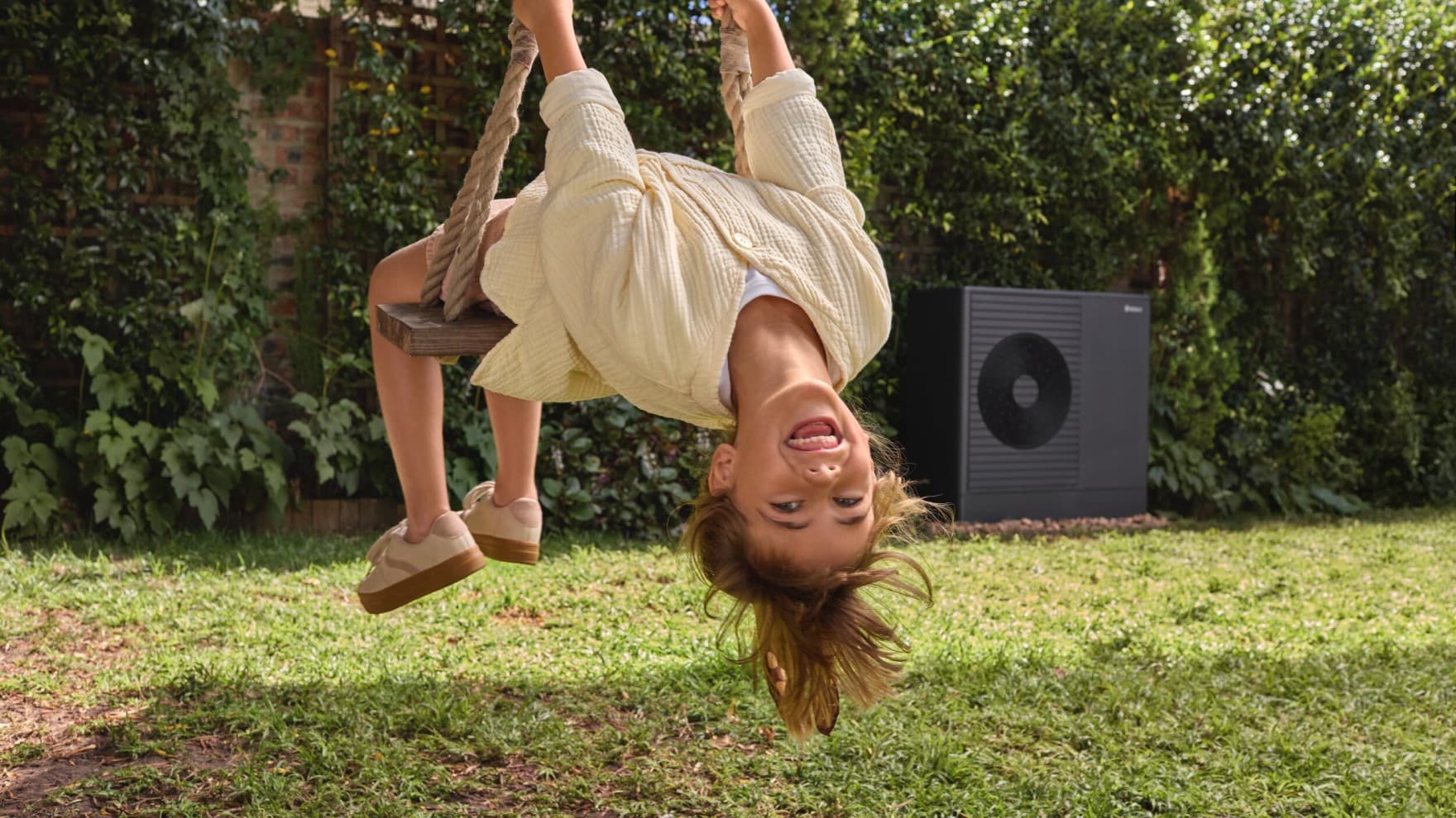 Girl on a swing with a heat pump in the background