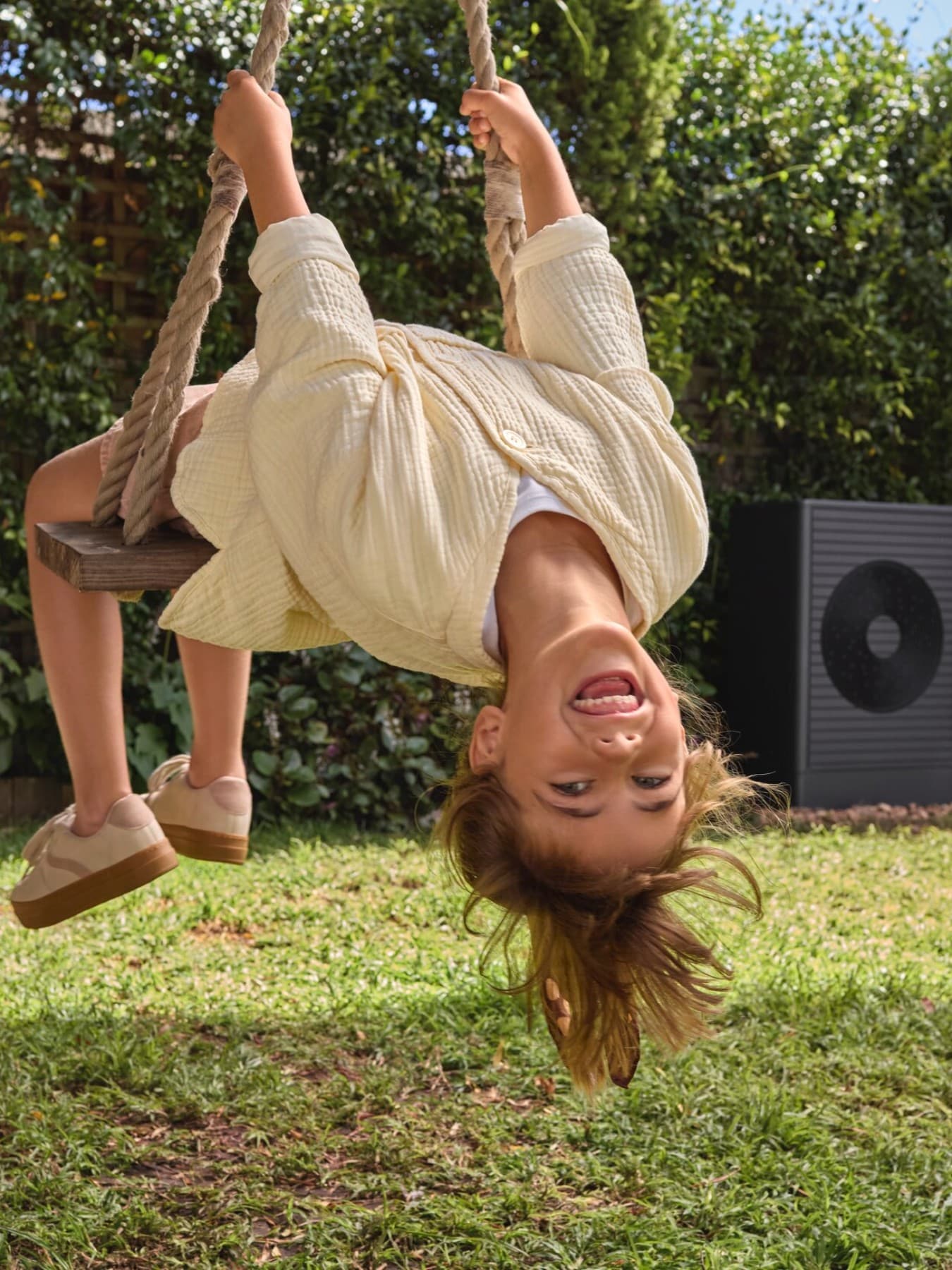 A child on a swing in the yard in front of a heat pump