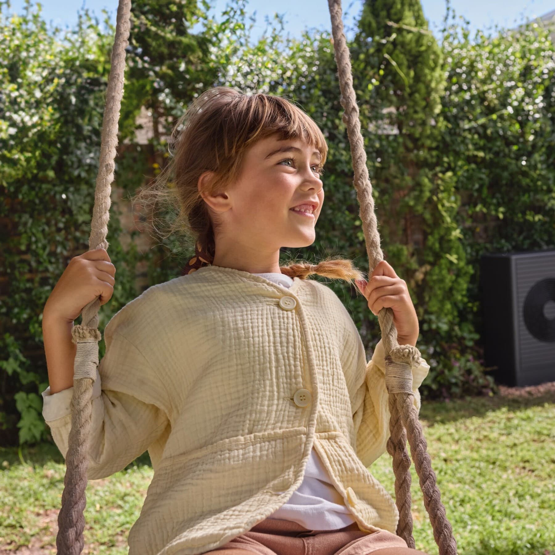 Children on a swing with a heat pump in the background