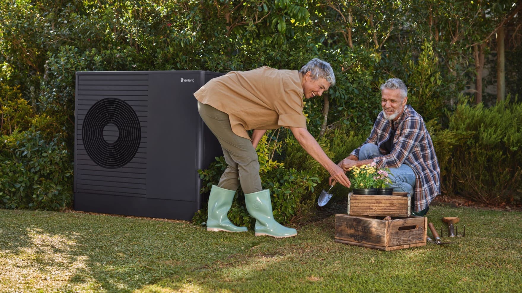 Old couple gardening with heat pump next in the background