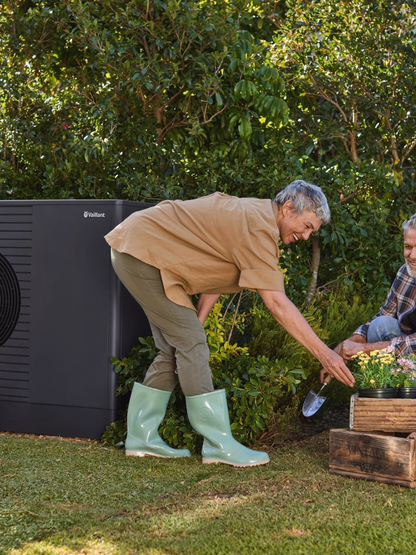 Old couple gardening with heat pump next in the background