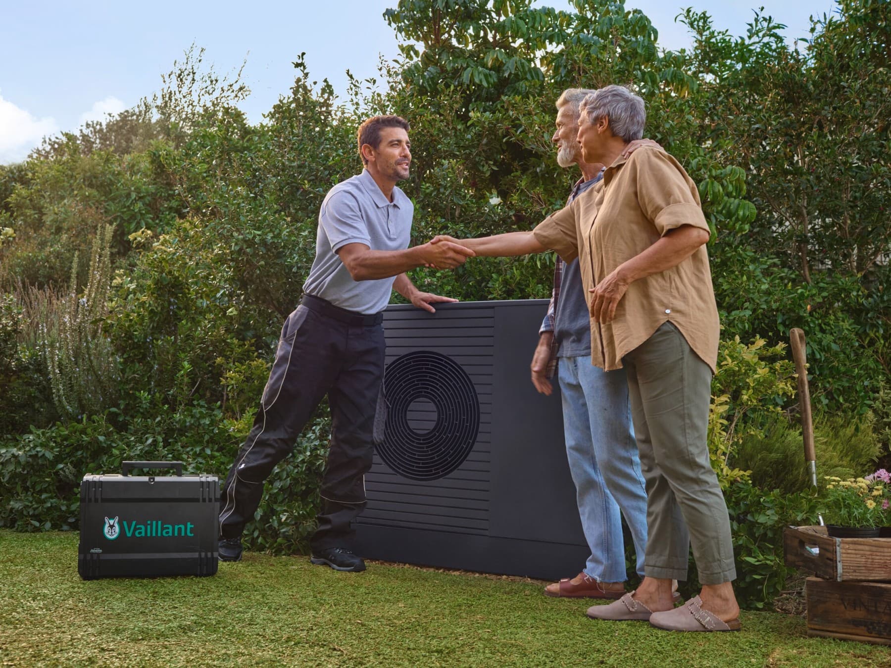 People handshaking in front of a heat pump in the garden