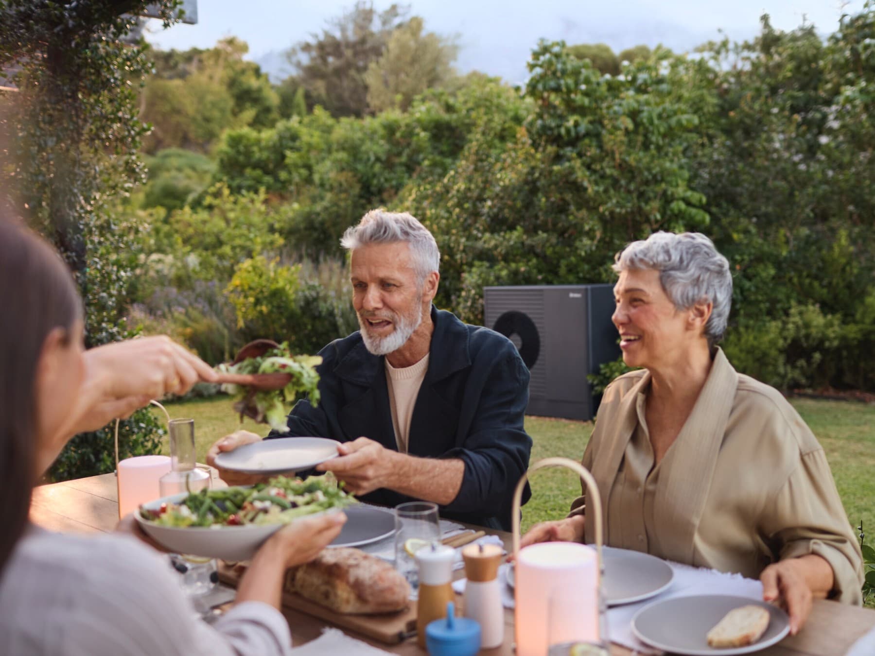 People dining in their garden, enjoying the silence of their heat pump.