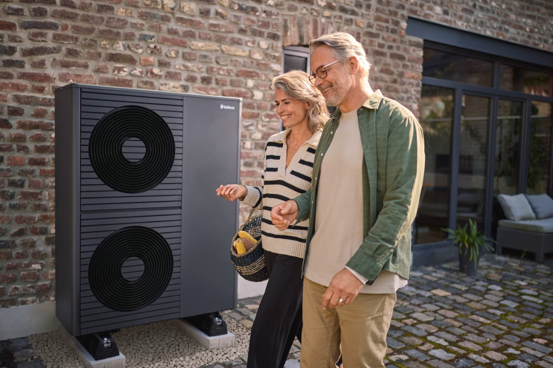 Middle-aged couple in front of heat pump in front of house