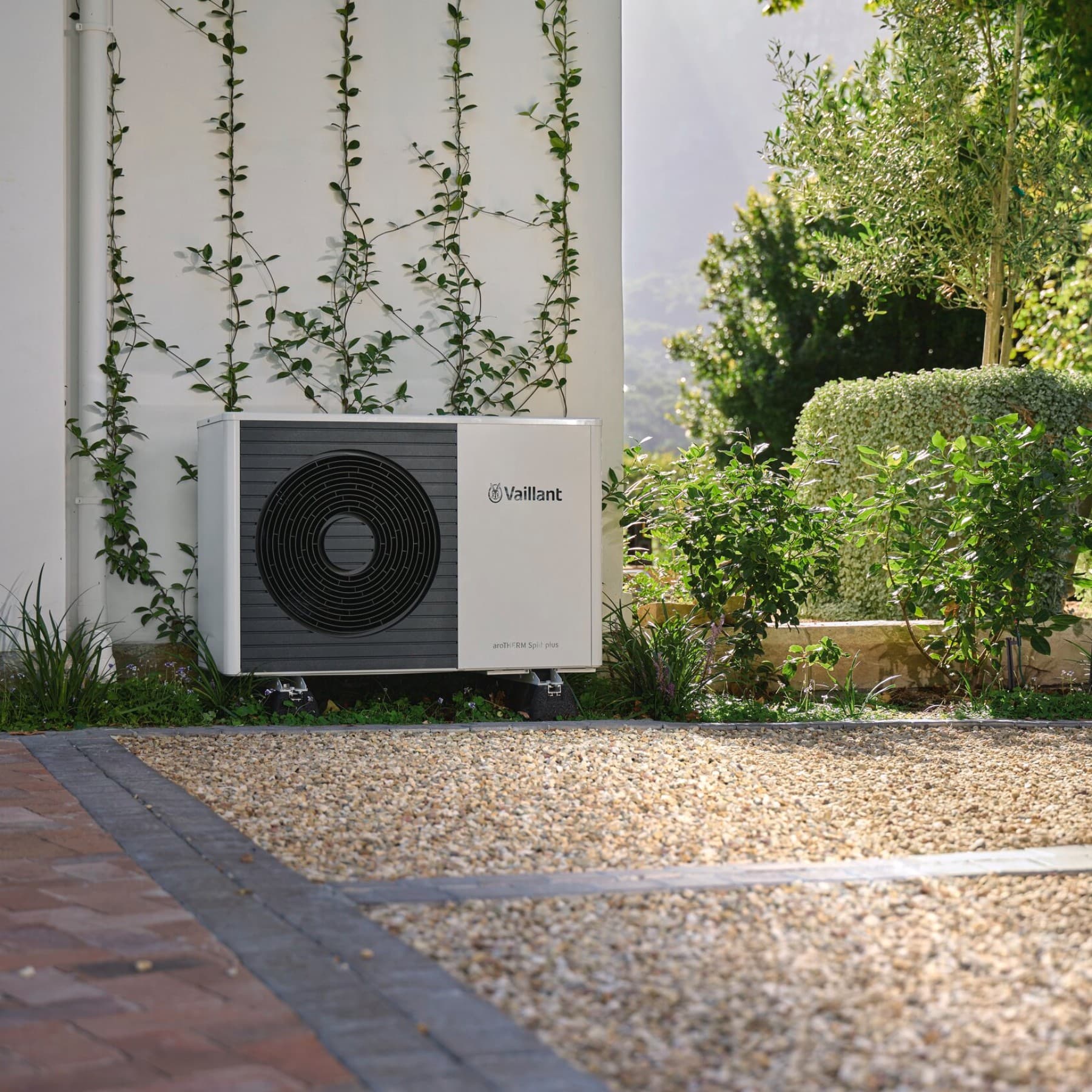 Pompe à chaleur Vaillant installée devant un mur dans un jardin