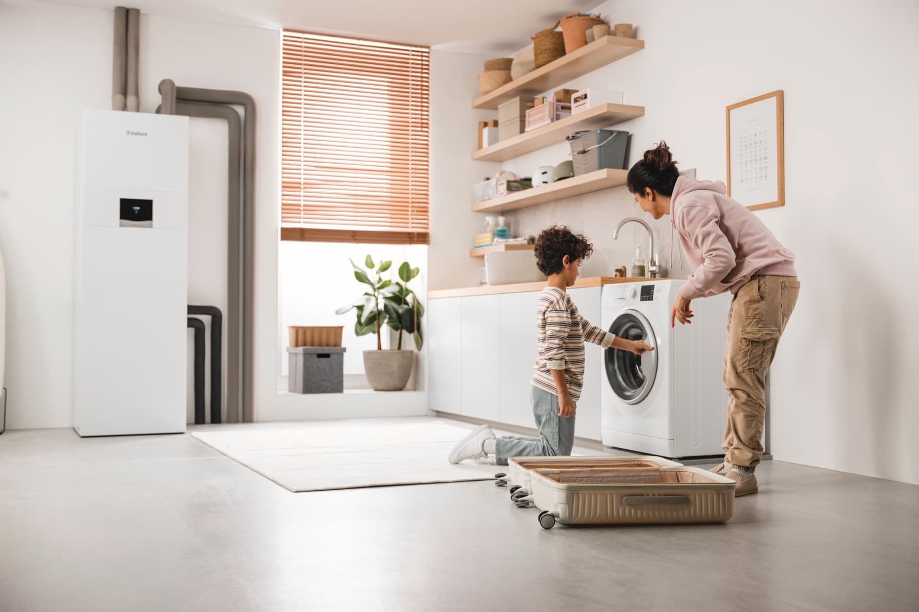 Mother and son checking the washing machine with a ground-source heat pump in the background