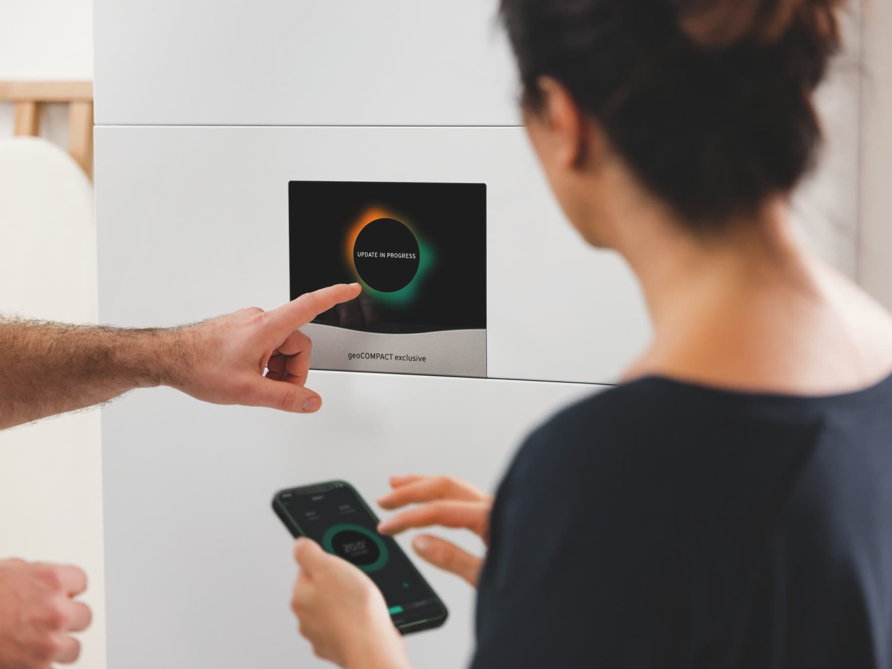 Display of geoCOMPACT heat pump and woman with smartphone in hand