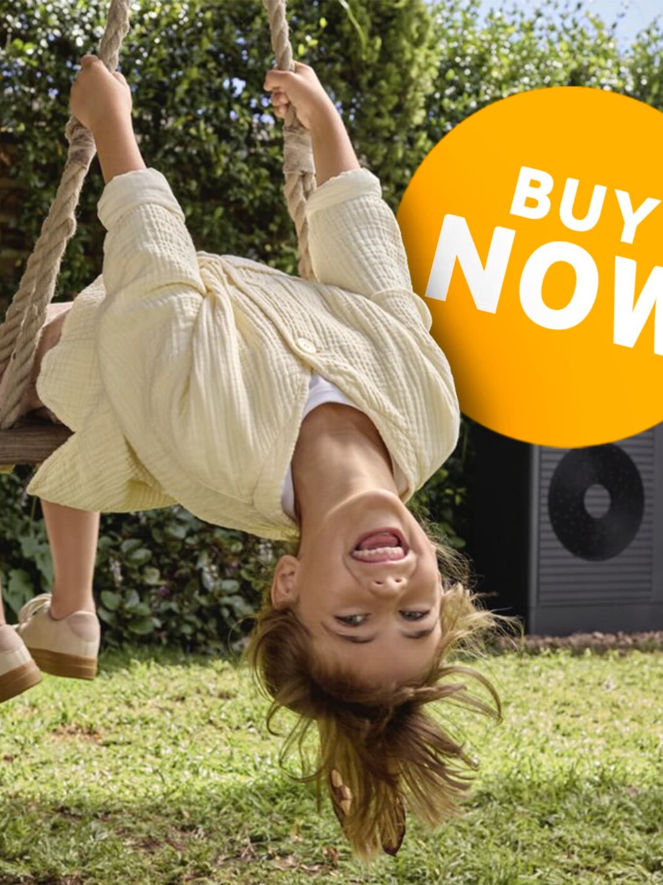 Child on a swing in the garden in front of a heat pump