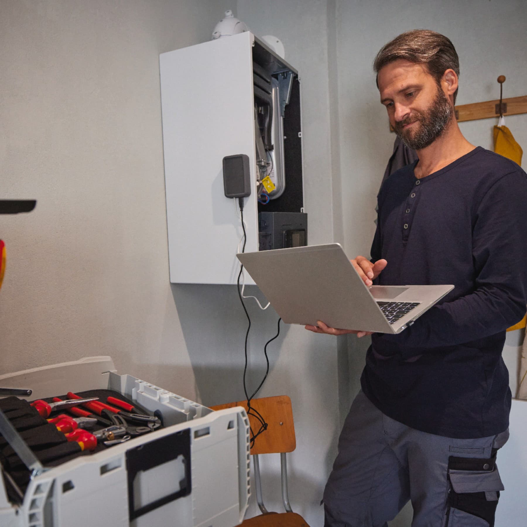 Service technician working on heat pump in front of man