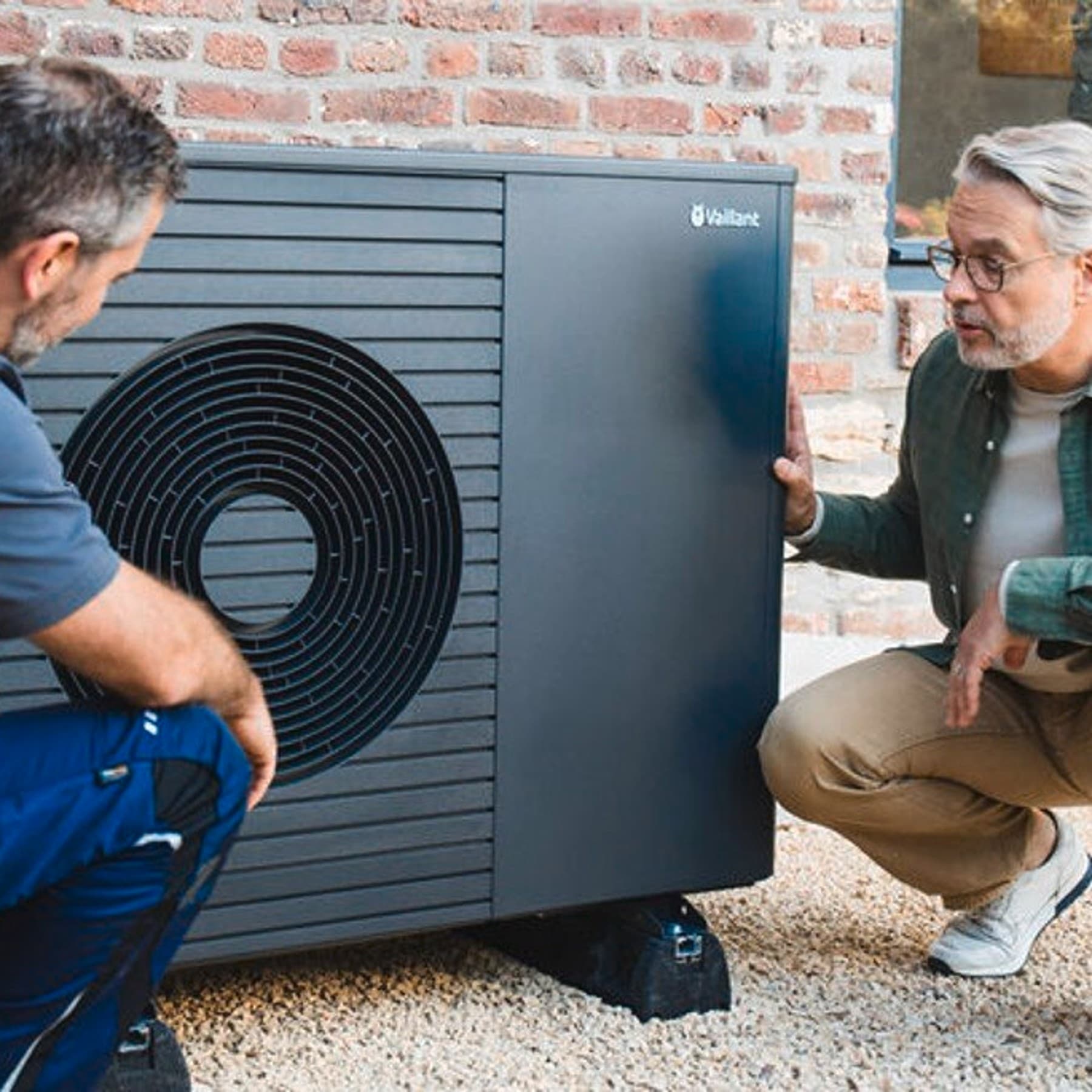 Installer and homeowner kneeling in front of heat pump