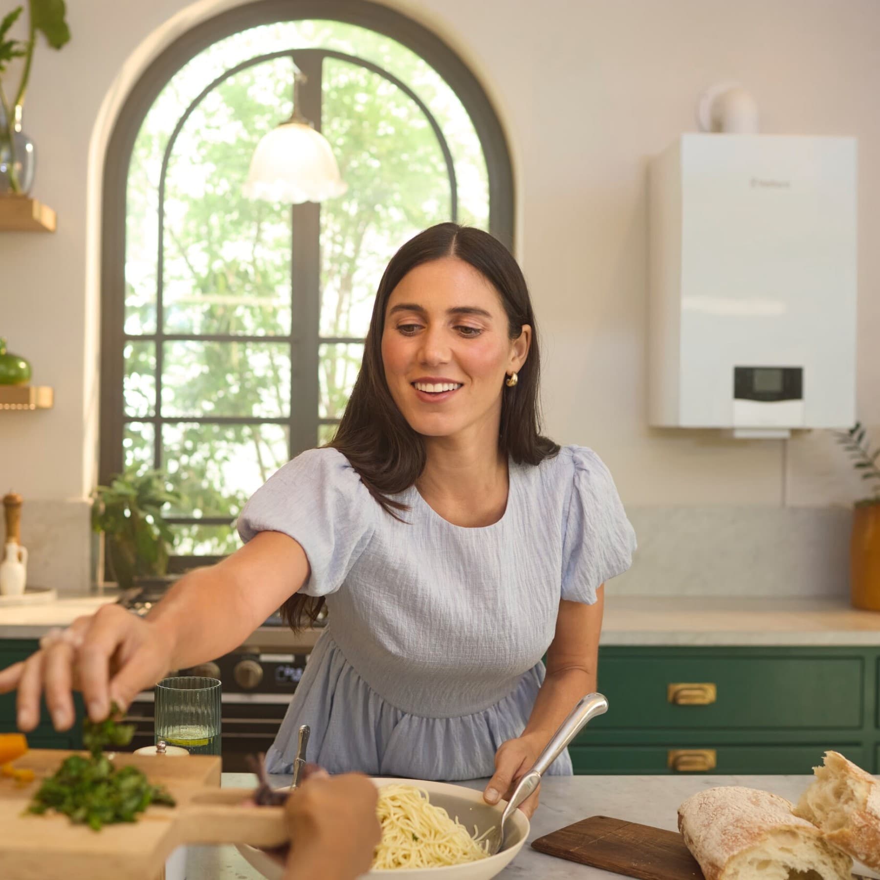 A woman is cooking in the kitchen - in the background a Vaillant ecoTEC plus boiler